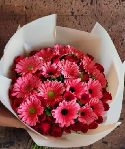 Ramo de 35 rosas rojas y 15 gerberas de colores brillantes con follaje verde para envío sin costo en Ciudad Juárez.