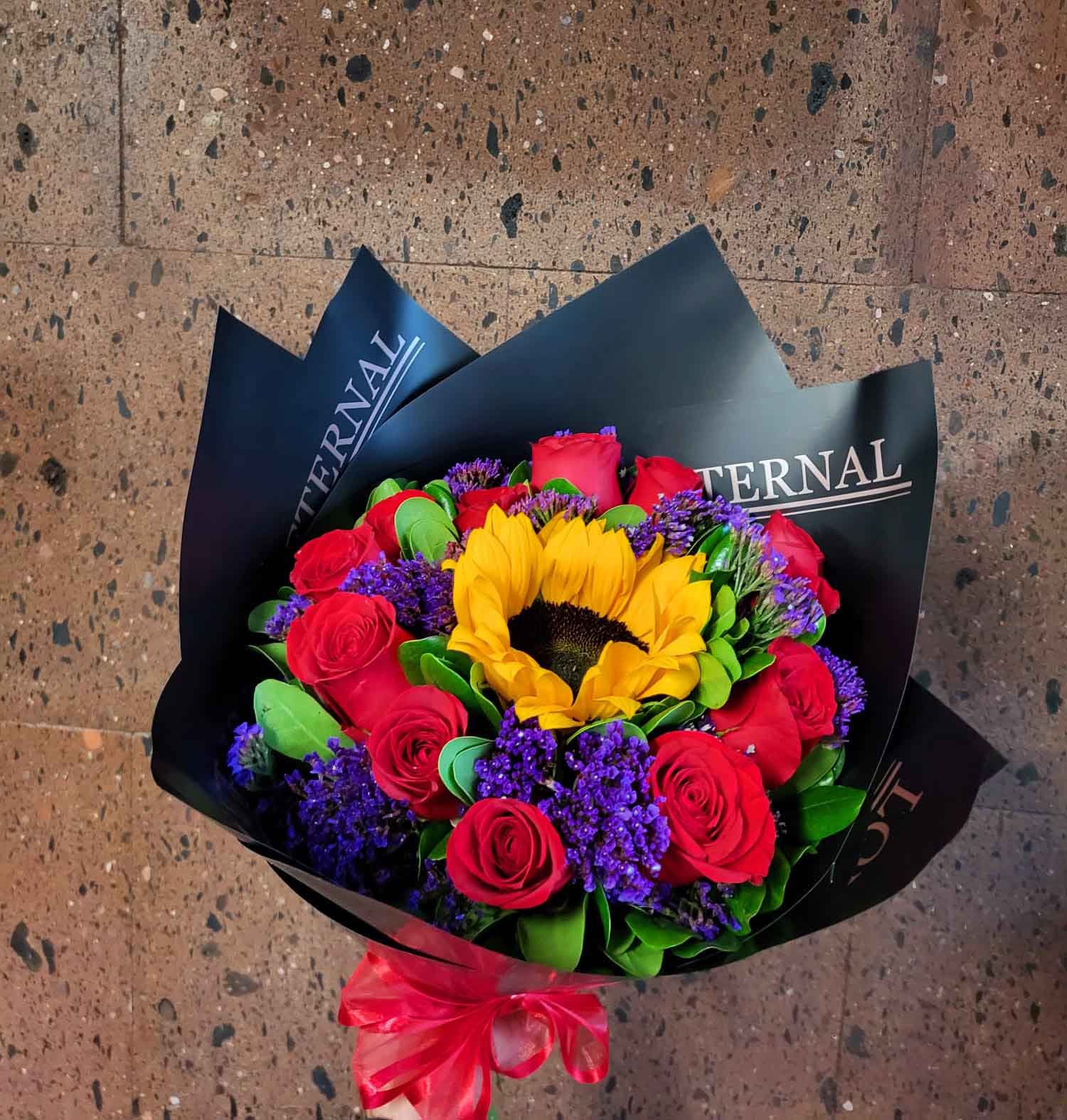 Ramo de 1 girasol brillante rodeado de 12 rosas rojas premium para envío sin costo en Ciudad Juárez.