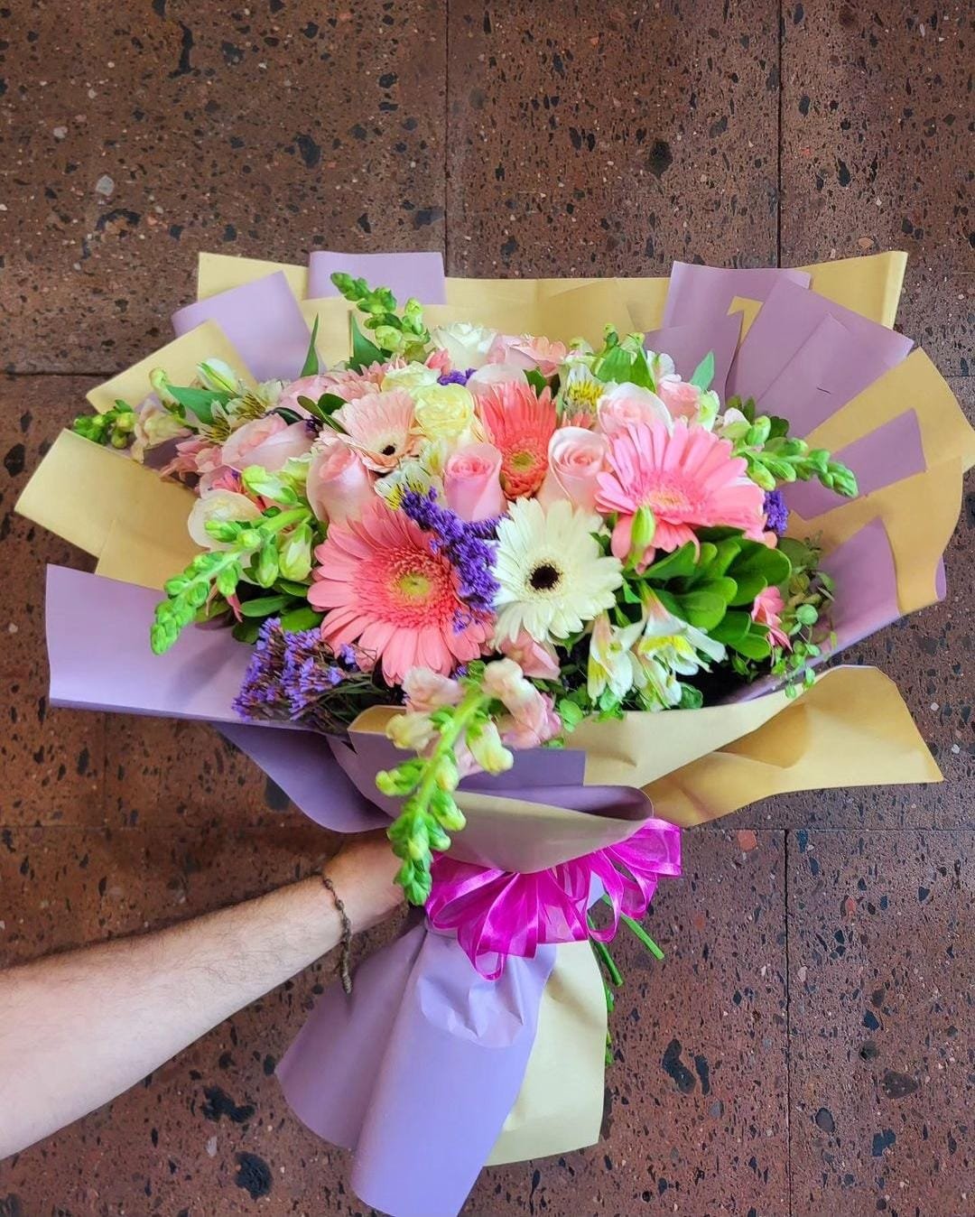 Ramo de flores con rosas rojas, gerberas de colores y flores de perrito blancas con follaje para envío sin costo en Ciudad Juárez.